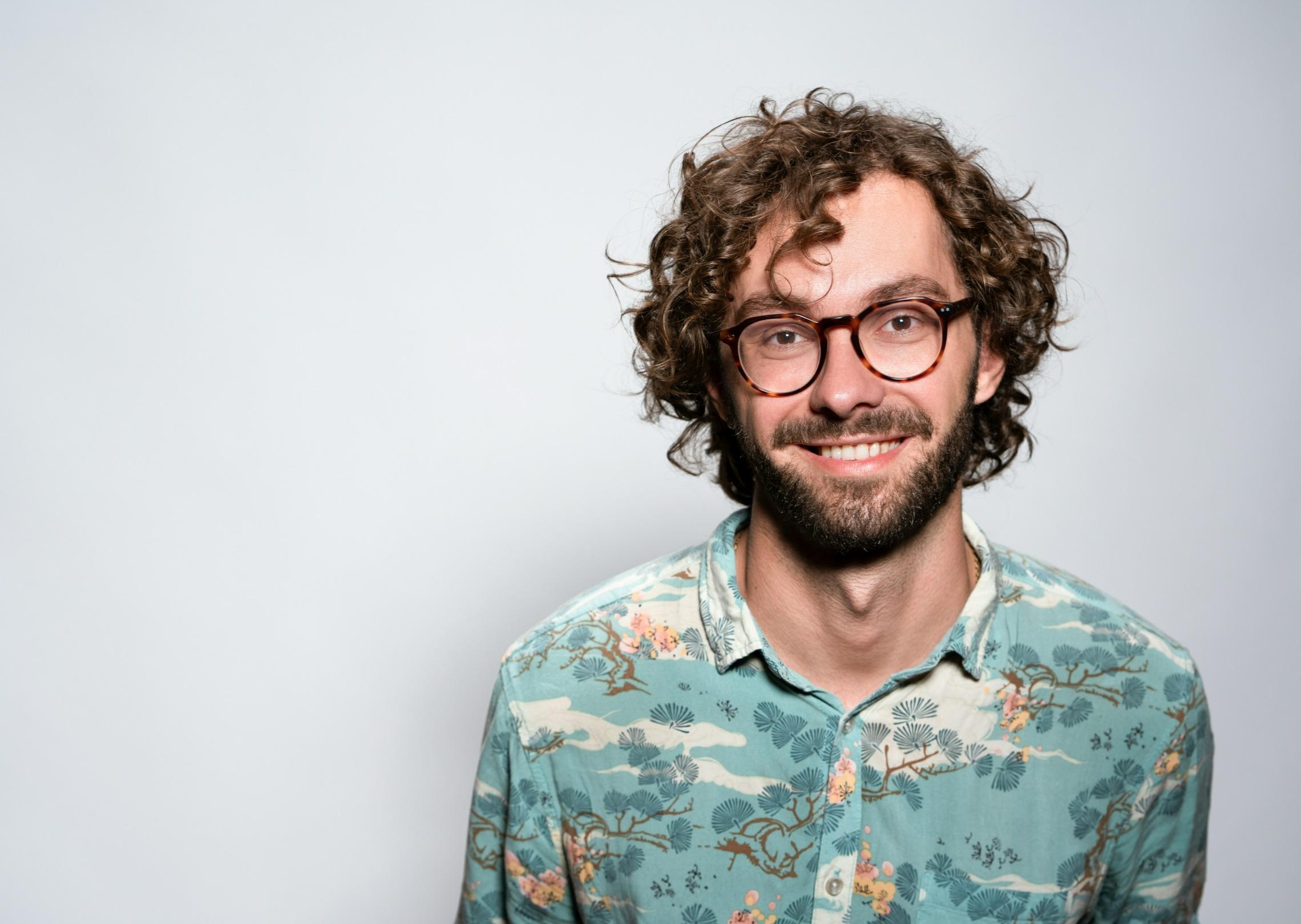 Generate a profile picture of a male with curly hair and glasses