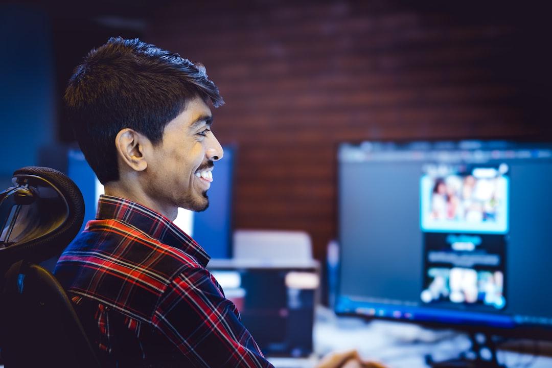 A person smiling while editing a video on a laptop, with graphic elements floating around the screen