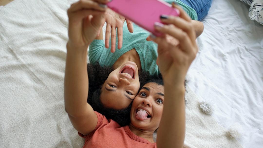 Ein Vater und seine Tochter im Teenageralter machen ein lustiges Selfie mit übertriebener Mimik.