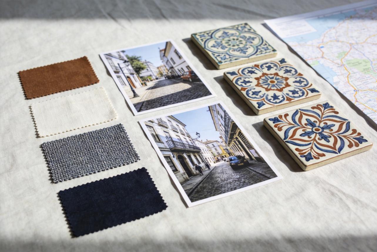 Fabric swatches, street photos, patterned tiles, and a map arranged on a tabletop