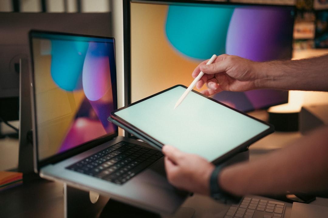 A person editing a video on a laptop with colorful visual effects on the screen